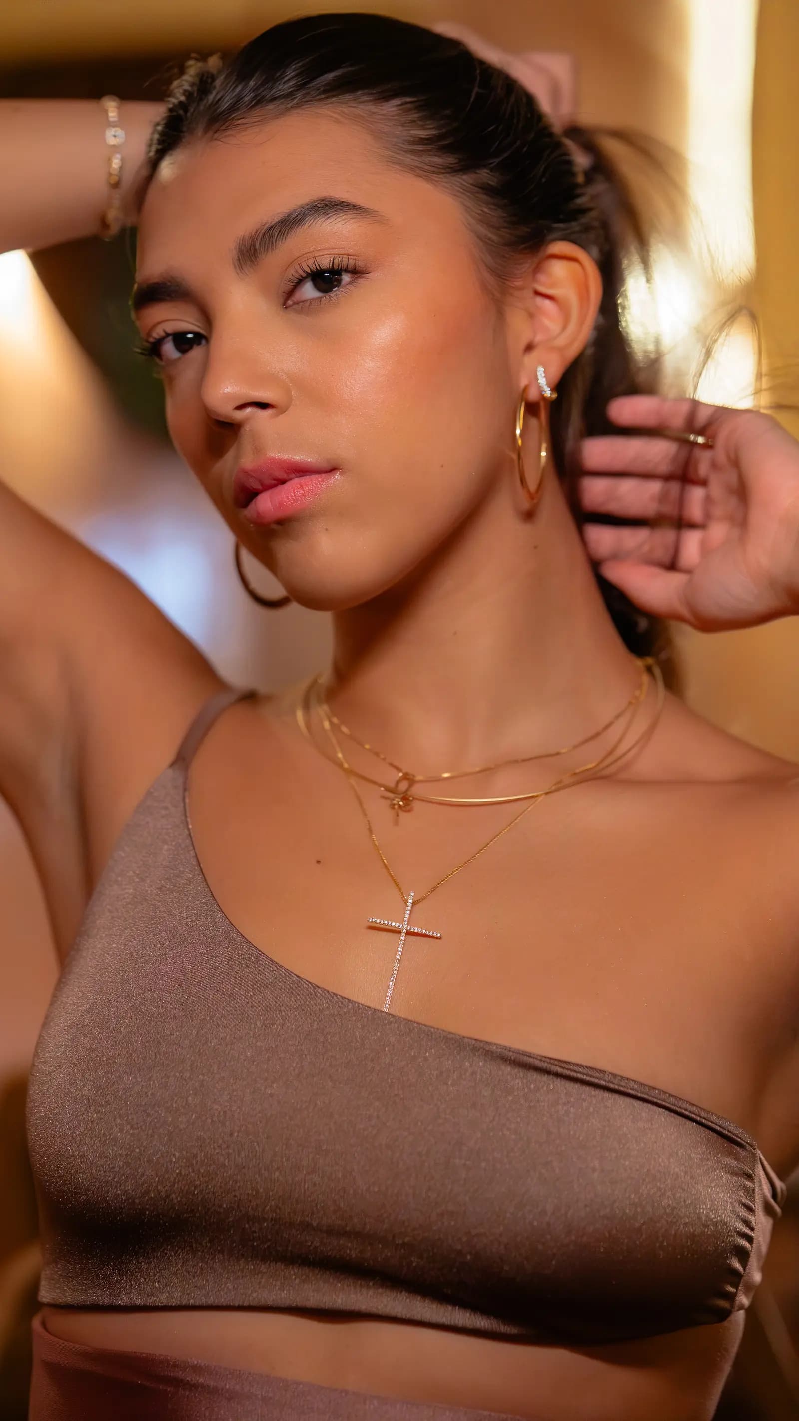 Modelo con argollas y collar de cruz en oro 18K